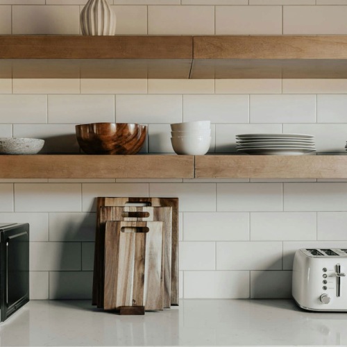 a kitchen counter with floating shelves, dishes and appliances