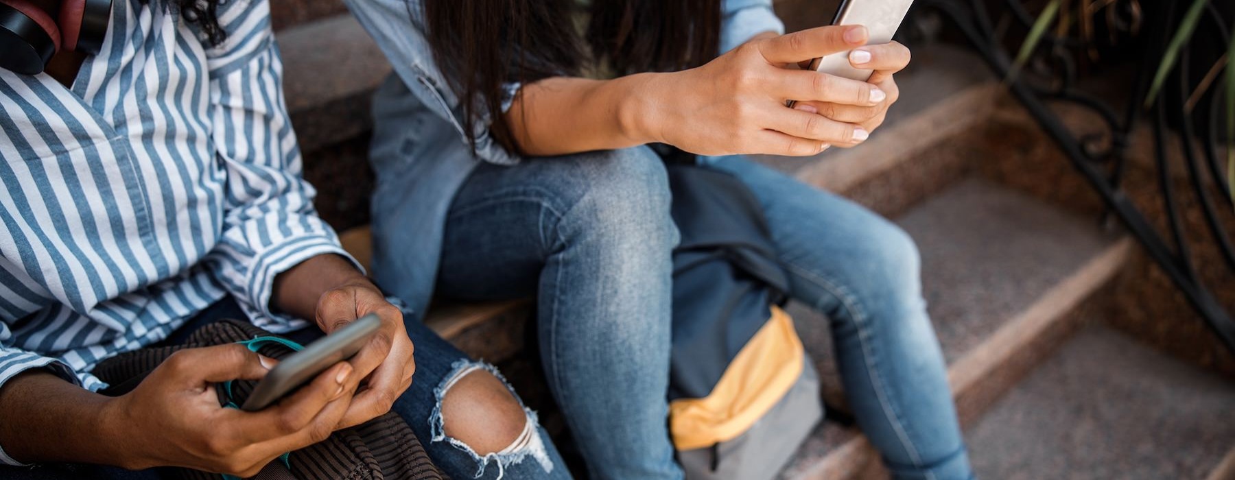 a group of people sitting on the sidewalk looking at their phones