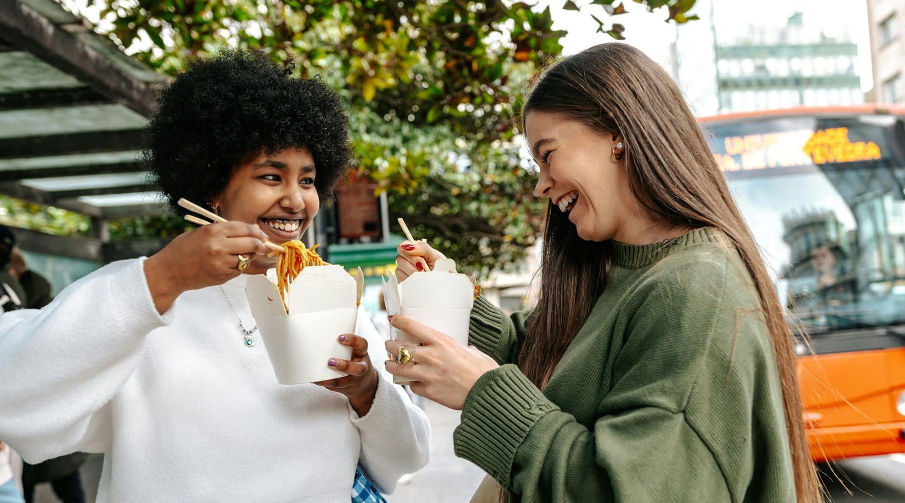 two women eating food in a city